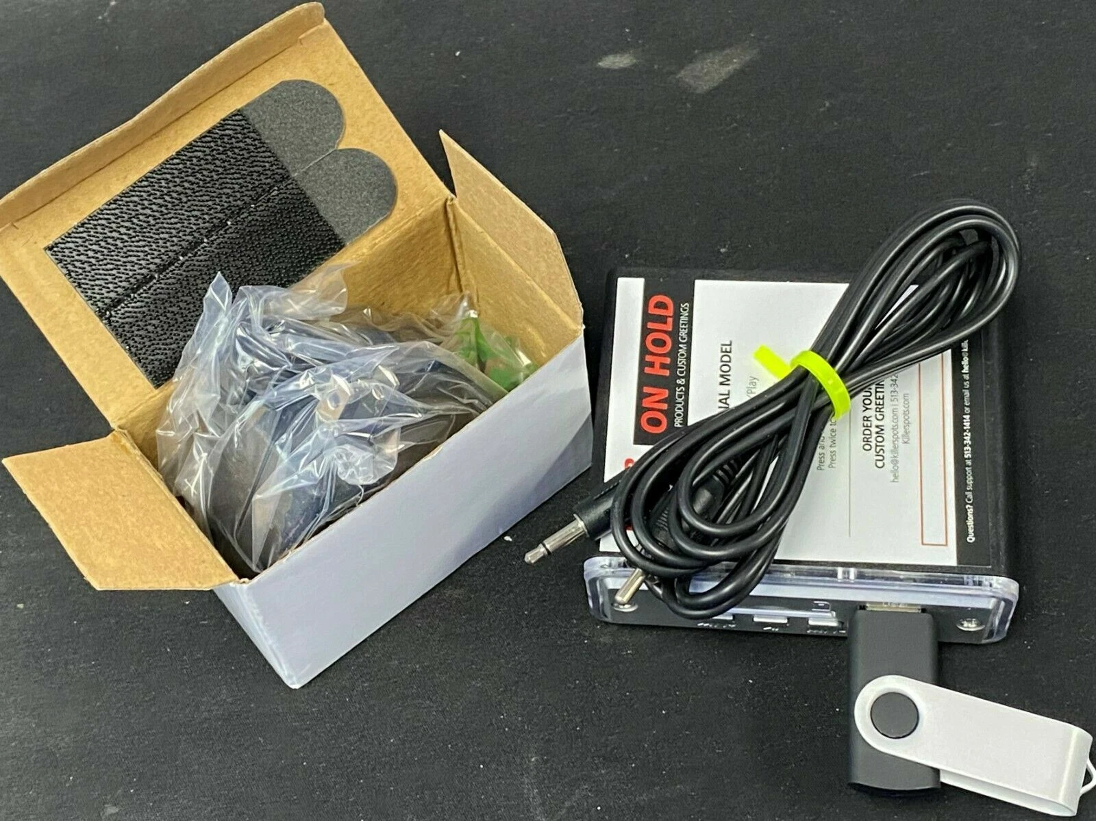 Killerspots On Hold Pro — player, mounting strip, audio cable, and USB drive in the box